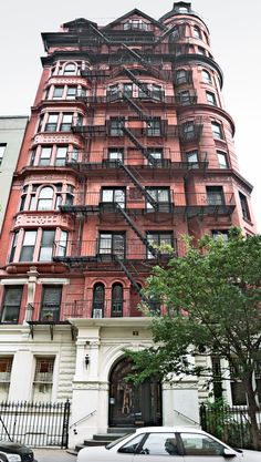 an apartment building with many windows and balconies on the top floor, next to cars parked in front of it