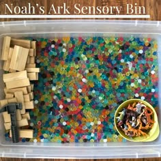 a plastic container filled with lots of different colored beads and wooden toy blocks on top of a table