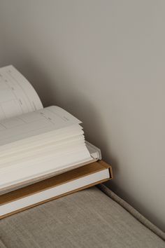 a stack of papers sitting on top of a wooden table next to a white wall