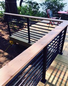 a wooden deck with metal railing and chairs