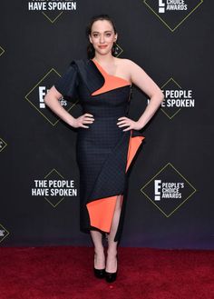 a woman in an orange and black dress poses on the red carpet at people's choice awards