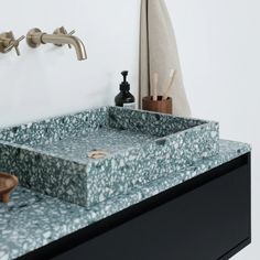 a bathroom sink with two faucets and soap dispensers on the wall