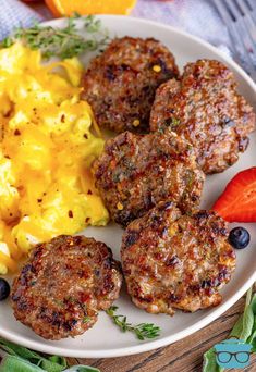 a white plate topped with meat patties next to carrots and macaroni