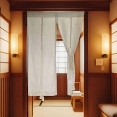 an open door leading to a room with wooden paneling and white drapes on the windows