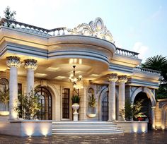 a large white building with columns and lights on the front porch, surrounded by greenery