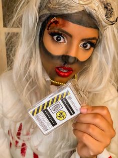 a woman with white hair and makeup holding up a card