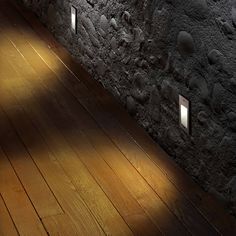 the light shines brightly on an empty room with wood flooring and stone walls