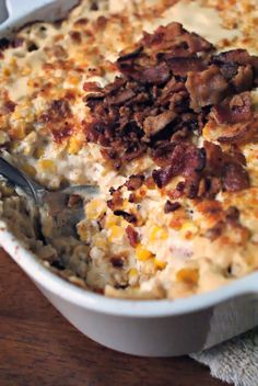 a casserole dish with meat and cheese in it on a wooden table next to a fork