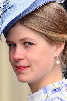 a close up of a woman wearing a blue hat with flowers and pearls on it