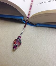 an open book with a purple beaded necklace on it