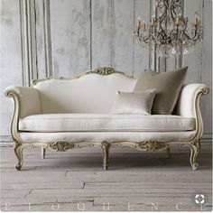 a white couch sitting on top of a wooden floor next to a chandelier