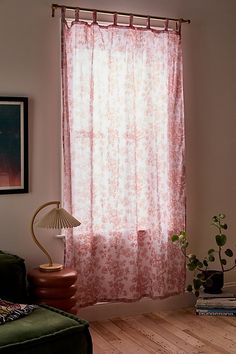 a living room with a green couch and red curtains