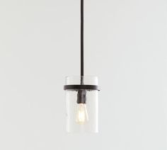 a small glass light hanging from a black ceiling fixture with a white wall in the background