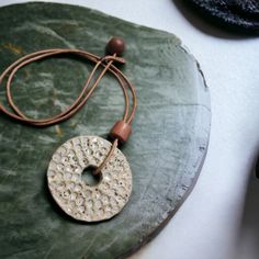 a green leaf with a pendant on it sitting on a table next to other items