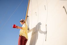 a woman standing on the side of a boat holding a red cup in her hand