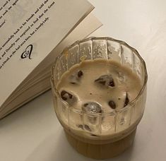 a drink in a glass next to an open book