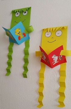 two paper monsters hanging on the wall next to each other, one reading a book