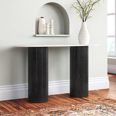 a white vase sitting on top of a table next to a black and white shelf