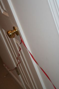 a door handle with a red string attached to it and a white wall in the background