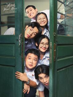 a group of people standing in front of a green door with their heads sticking out