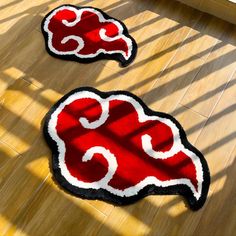 two red and black rugs sitting on top of a wooden floor next to each other