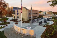 an aerial view of a building with flags flying in the wind and landscaping around it