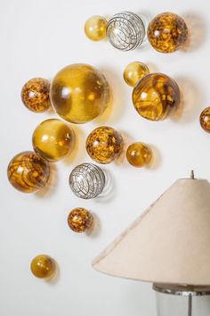 a lamp and some glass balls on a white surface with a light shade in front of it