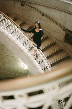 a woman is standing on the top of a spiral stair case in an old building