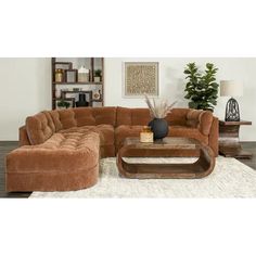 a living room with a large sectional couch and coffee table in front of a white rug