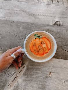 a hand holding a cup with a pumpkin drawn on it