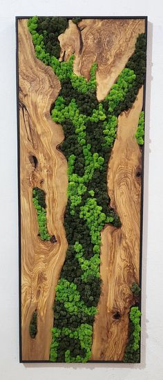 a piece of wood with green plants growing on it's sides in the shape of a river