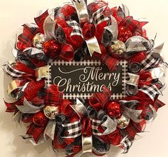 a red and black christmas wreath hanging on the side of a wall with merry christmas written on it