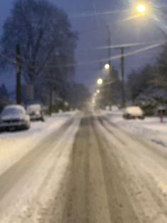 a snowy street with cars parked on the side and one car driving down the road