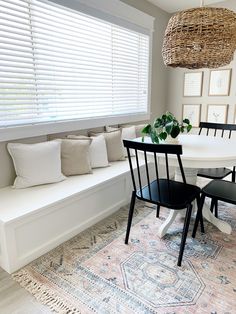 a dining room table with four chairs and a bench in front of the window,