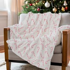 a white blanket with pink candy canes on it sitting in front of a christmas tree