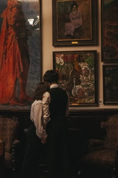 two people are looking at paintings on the wall