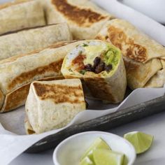 some food is laying out on a tray with limes and other items around it