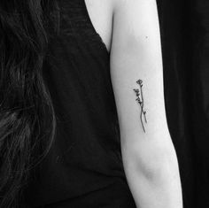 a black and white photo of a woman's arm with a single flower tattoo on it