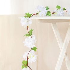 white flowers and green leaves on a wooden table