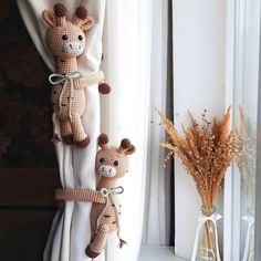 two stuffed giraffes are hanging on the curtain