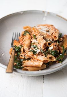 a pasta dish with spinach, meat and parmesan cheese on a plate