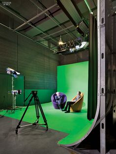 a person sitting in a chair on top of a green screen next to a tripod