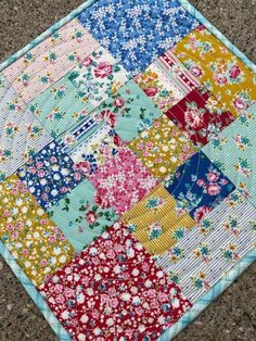 a patchwork quilt on the ground with flowers and blue, yellow, pink, red