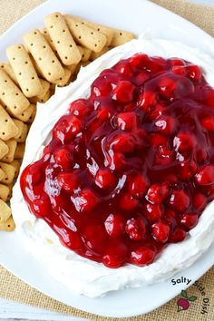 a plate with crackers and cheese covered in cherry sauce next to crackers on the side