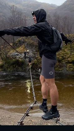 a man in black jacket standing on skis next to water and holding onto poles