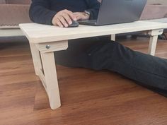 a man sitting on the floor using a laptop computer with his legs crossed and feet propped up