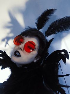 a woman with red sunglasses and feathers on her head