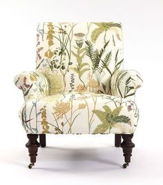 an upholstered chair with flowers and plants on the back, sitting in front of a white background