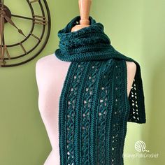 a green knitted scarf hanging on a mannequin's dummy next to a clock