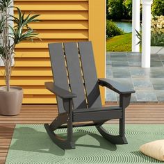 a black rocking chair sitting on top of a wooden floor next to a potted plant